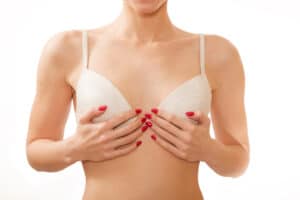 A woman in a white bra touching her chest after top surgery in Long Island
