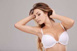 A woman in a white bra showing the results of breast augmentation with Motiva® implants