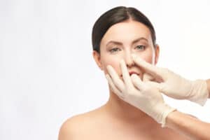 A surgeon examining a woman's nose before rhinoplasty in Long Island
