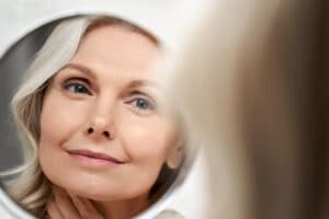 A woman looking in the mirror after an endoscopic brow lift in Long Island